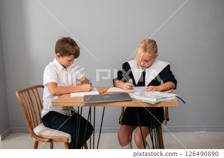 Children School Homework - Two children sit at a table doing homework. Children School Homework - Two children sit at a table doing homework. 126490890