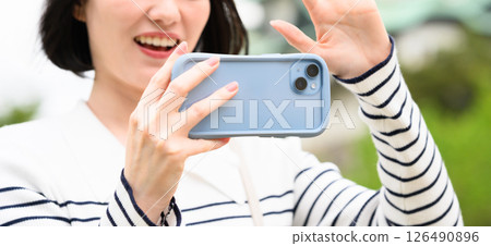 A woman taking a picture with a smartphone A woman taking a picture with a smartphone 126490896