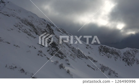 Mountains Snow Winter: Dramatic overcast sky illuminates snowy mountain range, showcasing rugged terrain. Mountains Snow Winter: Dramatic overcast sky illuminates snowy mountain range, showcasing rugged terrain. 126490996