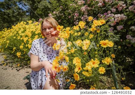 A woman is sitting in a field of yellow flowers A woman is sitting in a field of yellow flowers 126491032