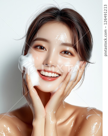 Skincare routine showcases glowing complexion and joyful expression of a young Korean woman during beauty regimen 126491213