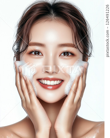 Korean woman enjoying a skincare routine while smiling with bubbly foam on her face in a bright setting 126491226
