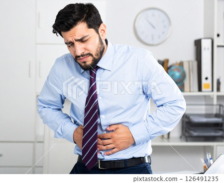 An office worker holding his stomach and looking distressed 126491235
