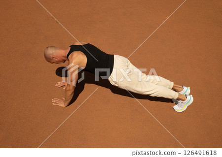 Athlete man or sports trainer push-up or plank exercise on sport field and looking away. Outdoors. Copy space. Summer. 126491618