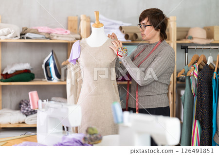 Seamstress shaping dress on mannequin in tailoring studio Seamstress shaping dress on mannequin in tailoring studio 126491851