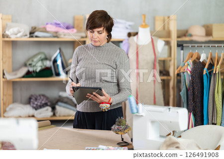 Woman tailor creates sketch of dress on tablet Woman tailor creates sketch of dress on tablet 126491908