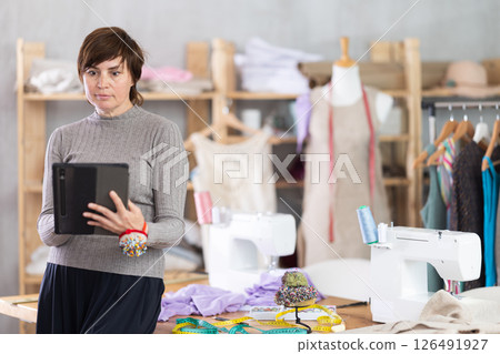 Woman tailor creates sketch of dress on tablet 126491927
