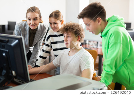 Teenagers studying with female teacher in information technology class 126492040