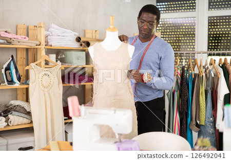 Dressmaker constructing custom dress on mannequin in sewing workshop 126492041