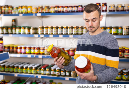 Adult man chooses pickled cucumbers and tomatoes 126492048