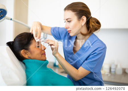 Cosmetologist using pencil for marking skin of patient Cosmetologist using pencil for marking skin of patient 126492078
