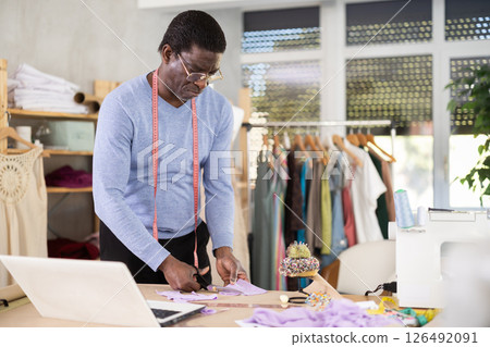 African man seamstress cuts fabric on cutting table 126492091