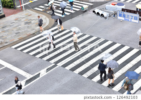 People walking with umbrellas through Ginza pedestrian precinct on a rainy day 126492103