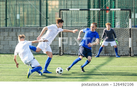 Teens playing soccer football match. Competition between two youth soccer teams 126492106