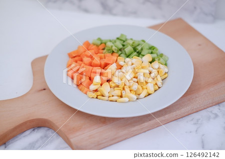 Frozen vegetables on a white plate on a white marble table. 126492142