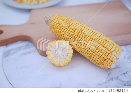 Corn on the cob and corn kernels on a white plate on a white background Corn on the cob and corn kernels on a white plate on a white background 126492154