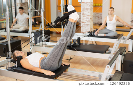 Girl doing exercises with feet in straps on Pilates reformer 126492256