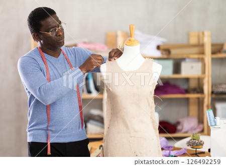 Experienced tailor shaping dress on mannequin in tailoring studio 126492259