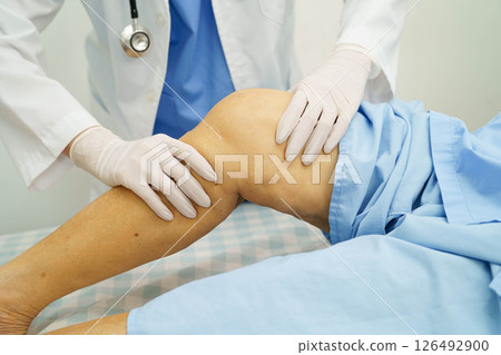 Doctor checking Asian elderly woman patient with scar knee replacement surgery in hospital. 126492900