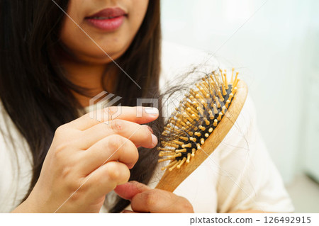 Asian woman have problem with long hair loss attach to comb brush. Asian woman have problem with long hair loss attach to comb brush. 126492915