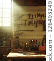 Tools arranged methodically on a backlit pegboard in a workshop during a late afternoon 126493249