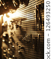 Tools arranged on a backlit pegboard creating an artistic display of shapes and shadows in a workspace 126493250