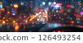 Raindrops glisten on a car window at night, illuminating city lights in vibrant colors 126493254