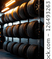 Upscale garage featuring an impressive display of tires on sleek metal racks in a modern automotive setting 126493263