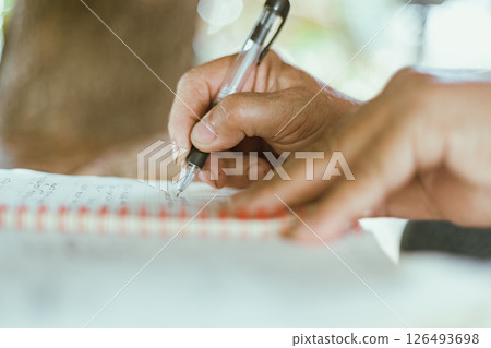 A hand writing on a notebook on a table A hand writing on a notebook on a table 126493698