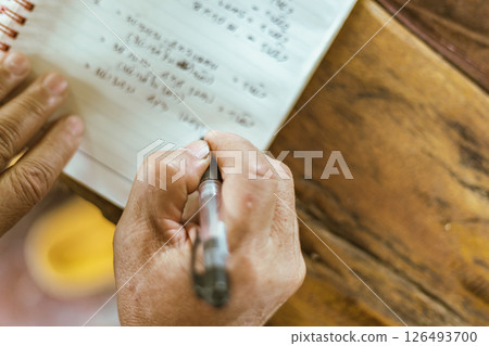 A hand writing on a notebook on a table 126493700