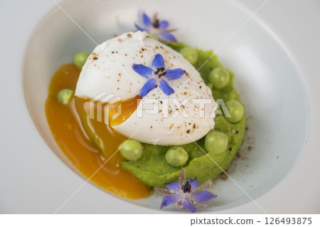 Delicious fresh pea puree topped with a perfectly poached egg and garnished with borage flowers for 126493875