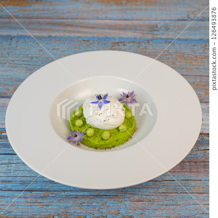 Delicious fresh pea puree topped with a perfectly poached egg and garnished with borage flowers for Delicious fresh pea puree topped with a perfectly poached egg and garnished with borage flowers for 126493876