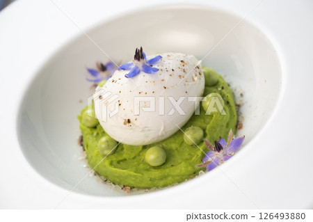 Delicious fresh pea puree topped with a perfectly poached egg and garnished with borage flowers for Delicious fresh pea puree topped with a perfectly poached egg and garnished with borage flowers for 126493880