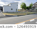 A vacant lot on the road side surrounded by houses 126493919