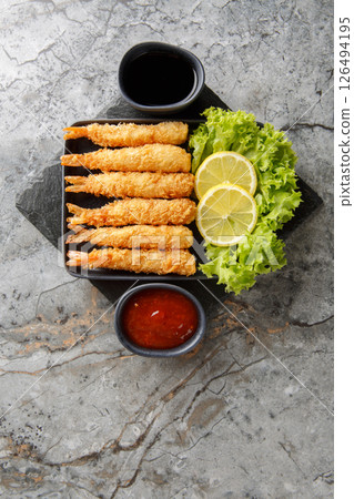 Crispy Japanese-style tempura shrimp made with homemade tempura batter closeup on plate. Vertical top view Crispy Japanese-style tempura shrimp made with homemade tempura batter closeup on plate. Vertical top view 126494195
