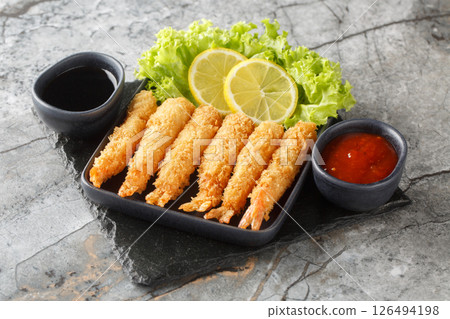 Tempura deep-fried EBI prawns with spiced sauces closeup on plate. Horizontal Tempura deep-fried EBI prawns with spiced sauces closeup on plate. Horizontal 126494198