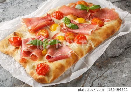 Fragrant homemade pinsa romana with tomato mix, prosciutto ham, mozzarella cheese and basil on parchment. horizontal Fragrant homemade pinsa romana with tomato mix, prosciutto ham, mozzarella cheese and basil on parchment. horizontal 126494221