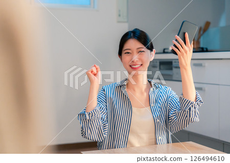 Overjoyed young woman holding smartphone at night at home 126494610