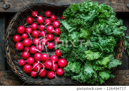 Fresh organic radishes and leafy kale arranged in a rustic woven basket on wooden surface Fresh organic radishes and leafy kale arranged in a rustic woven basket on wooden surface 126494717