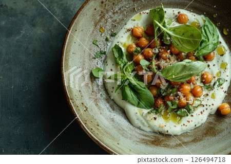 Creamy yogurt bowl topped with roasted chickpeas, fresh herbs, and olive oil drizzle 126494718