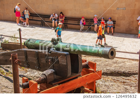 An ancient cannon stands on the pier near the fortress walls of the Bojnice castle. The old cannon is big. An ancient cannon stands on the pier near the fortress walls of the Bojnice castle. The old cannon is big. 126495632