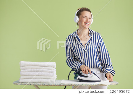 Woman enjoying music while ironing towels Woman enjoying music while ironing towels 126495672