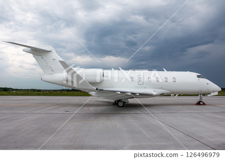 Modern white corporate airplane at the airport on a cloudy day 126496979