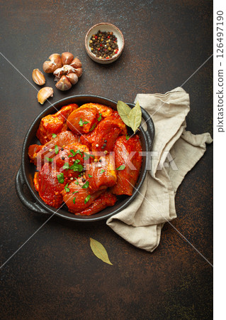 Raw uncooked chopped pieces of meat marinated with seasonings and parsley in black casserole dish top view on dark rustic background. Cooking ragout stew with marinated meat fillet pieces Raw uncooked chopped pieces of meat marinated with seasonings and parsley in black casserole dish top view on dark rustic background. Cooking ragout stew with marinated meat fillet pieces 126497190