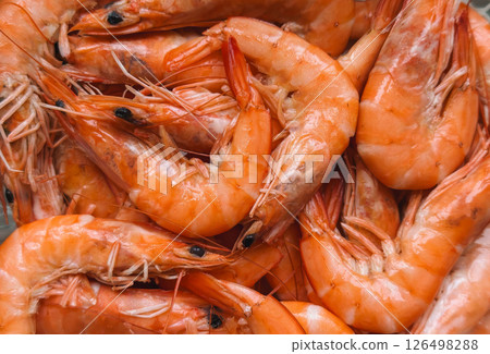 Close-up of a pile of fresh, cooked shrimp with vibrant orange shells and detailed textures 126498288