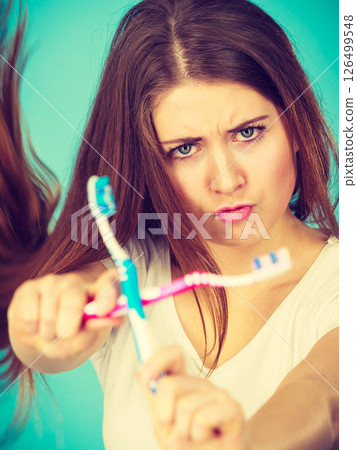 Woman holding two toothbrushes crossed 126499548