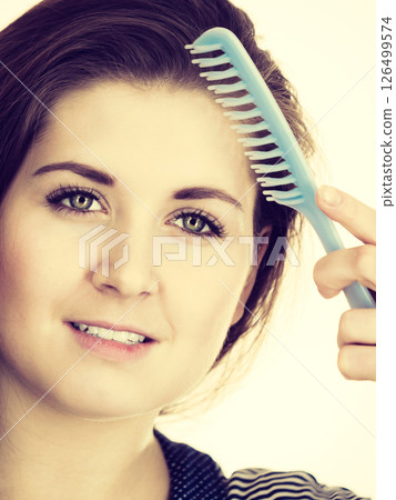 Woman brushing her long hair using comb Woman brushing her long hair using comb 126499574