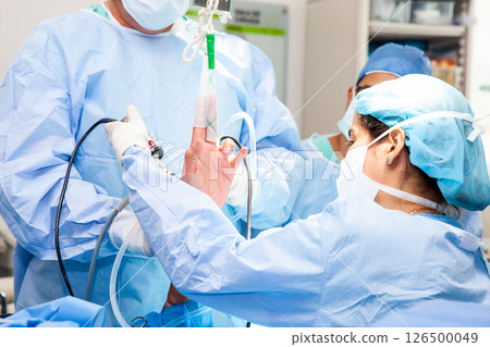 Group of orthopedic surgeons performing a wrist arthroscopy on a male patient. Female doctor performing a surgery. Orthopedic surgeon. Surgery and insurance concept. 126500049