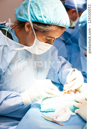 Female doctor performing a surgery. Orthopedic surgeon. Surgery and insurance concept. 126500051