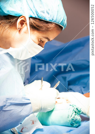 Female doctor performing a surgery. Orthopedic surgeon. Surgery and insurance concept. 126500052